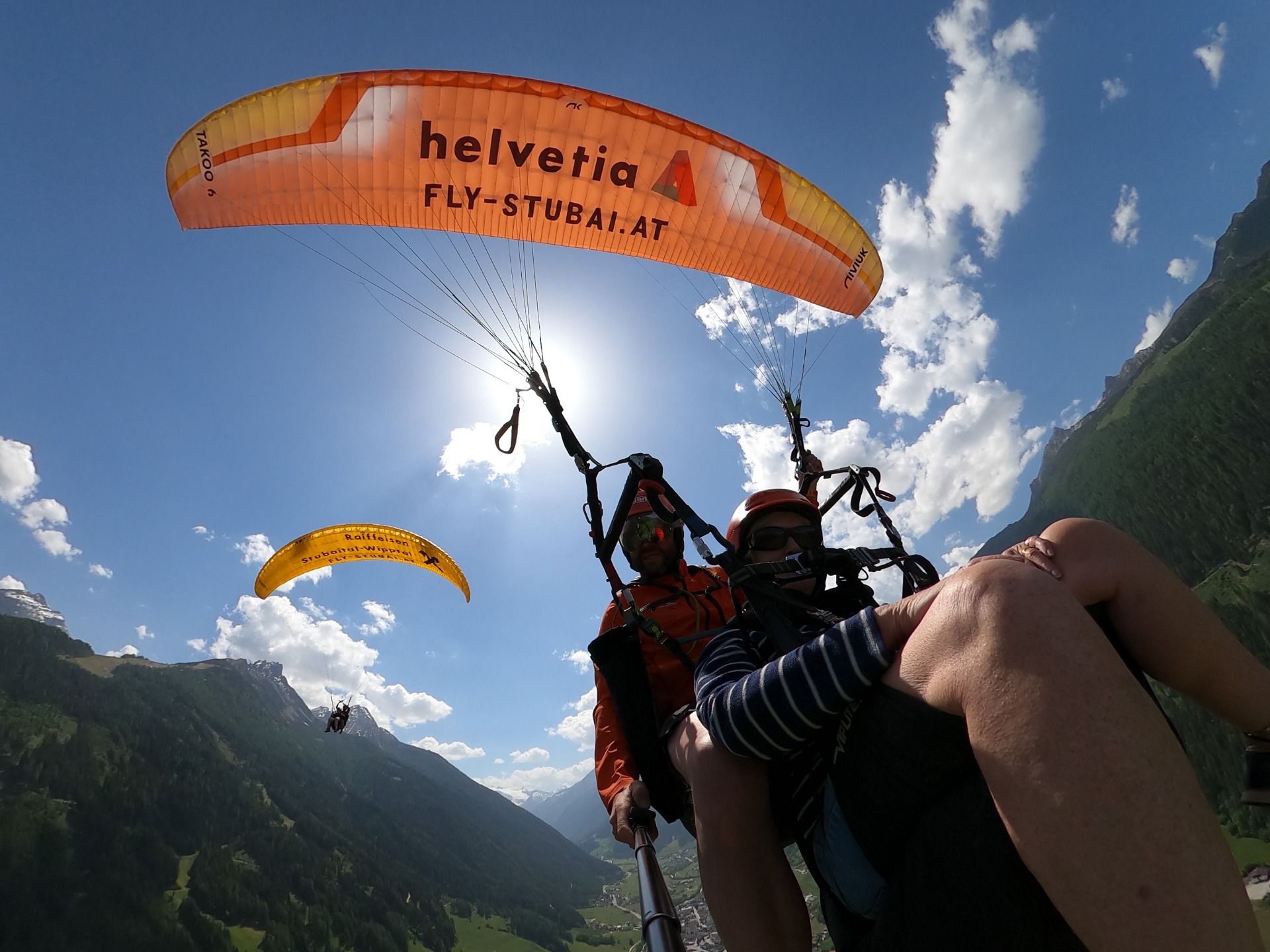 POV-Tandemflug mit großem orangefarbenem Schirm und Blick über das Tal bei Innsbruck